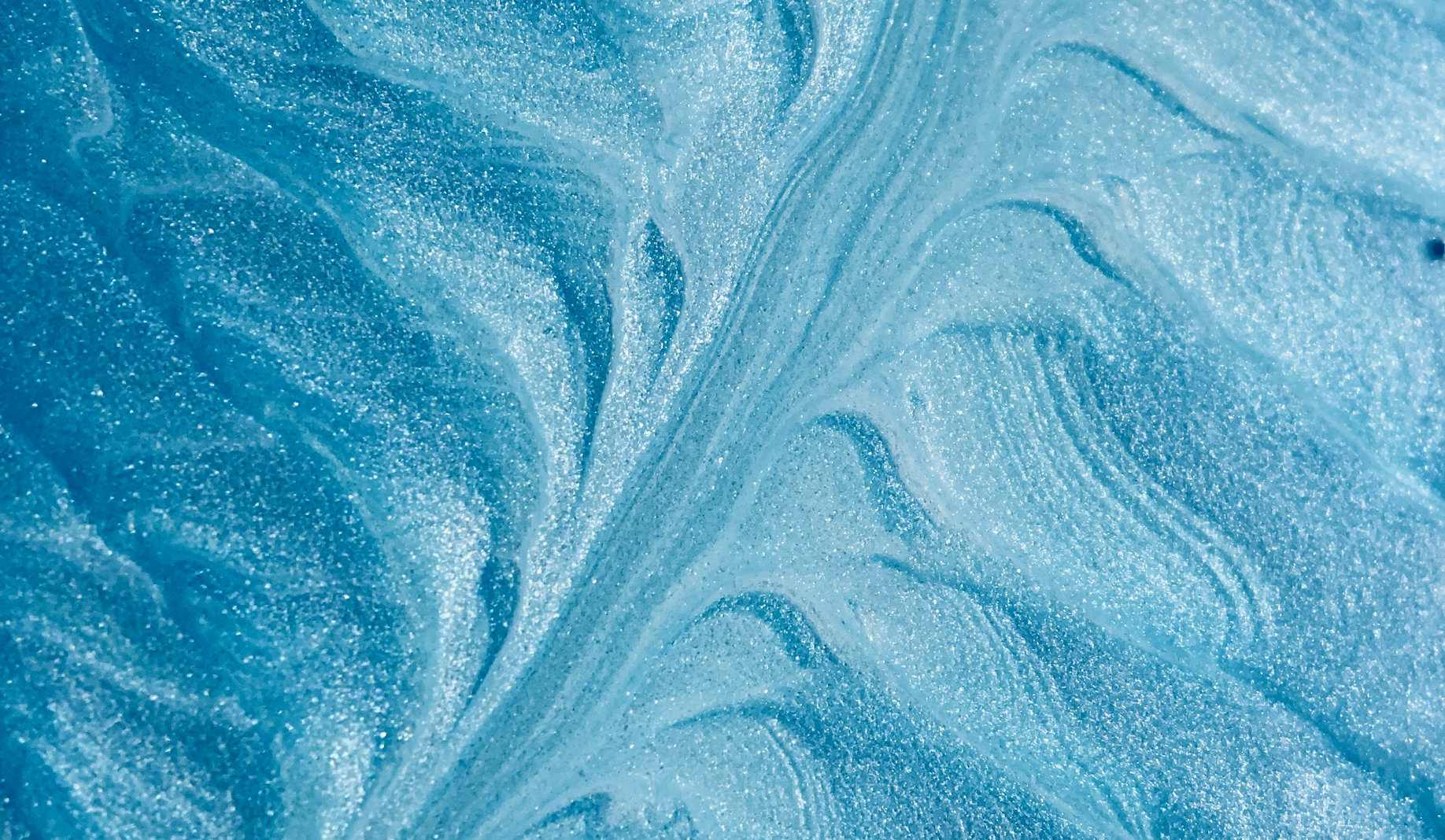 Textured swirls of shimmering blue resembling ice or water patterns